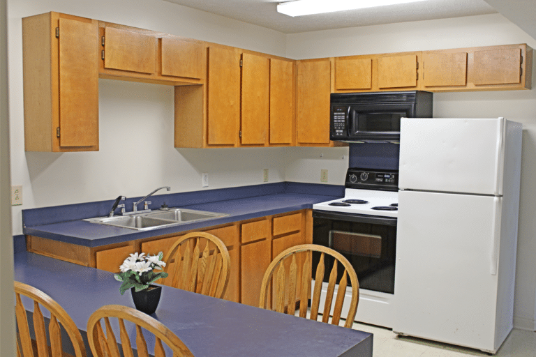 受托人大厅里一间公寓的厨房. 有冰箱、炉子、微波炉、水槽和桌子.