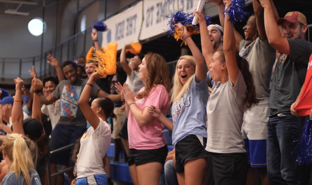 Group of students cheering at a game inside of the gym in the Moore Center.